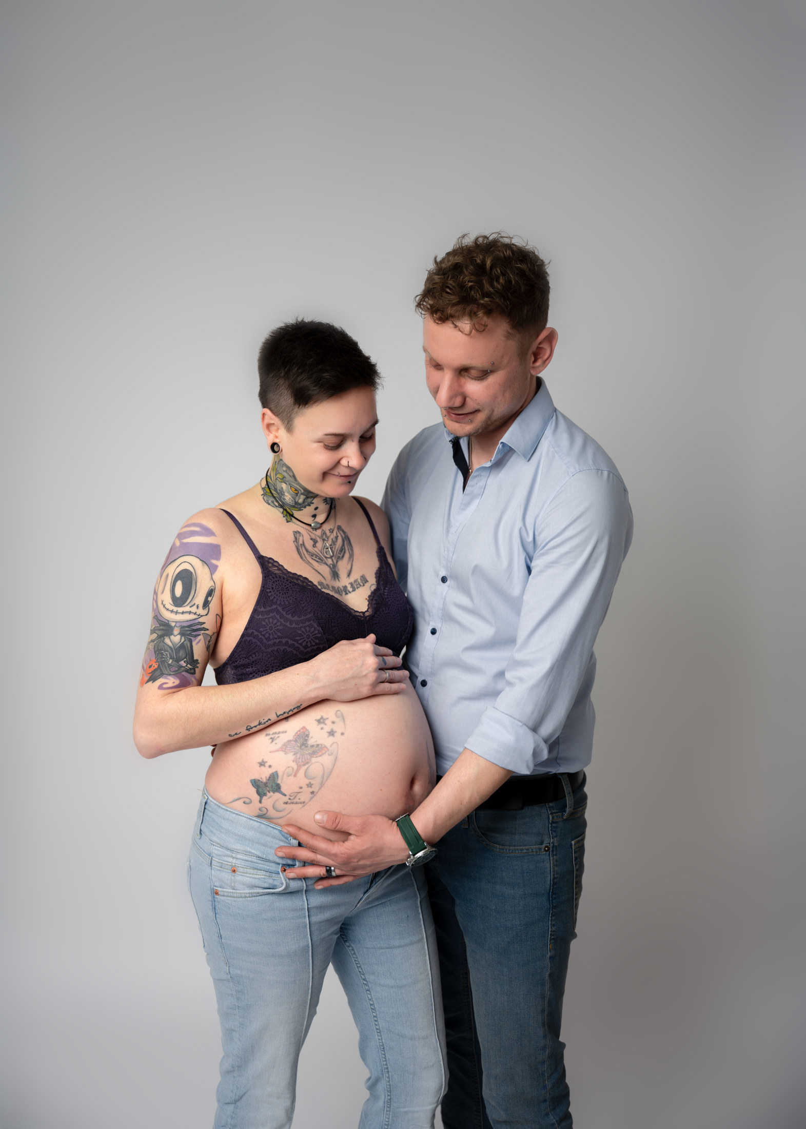 Paar betrachtet gemeinsam den Babybauch im Fotostudio