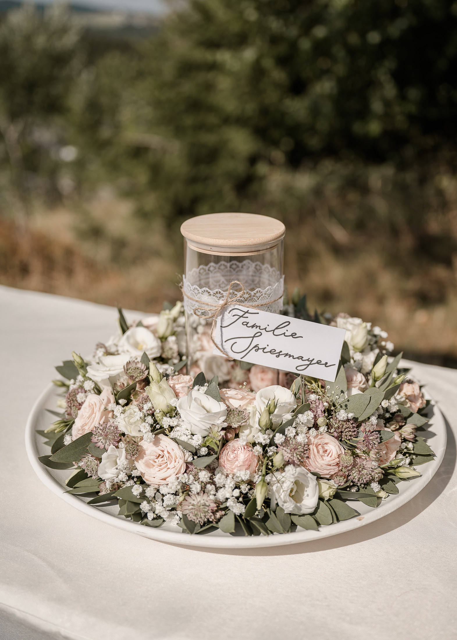 Blumenkranz mit Glas für die Sandzeremonie auf dem Trautisch