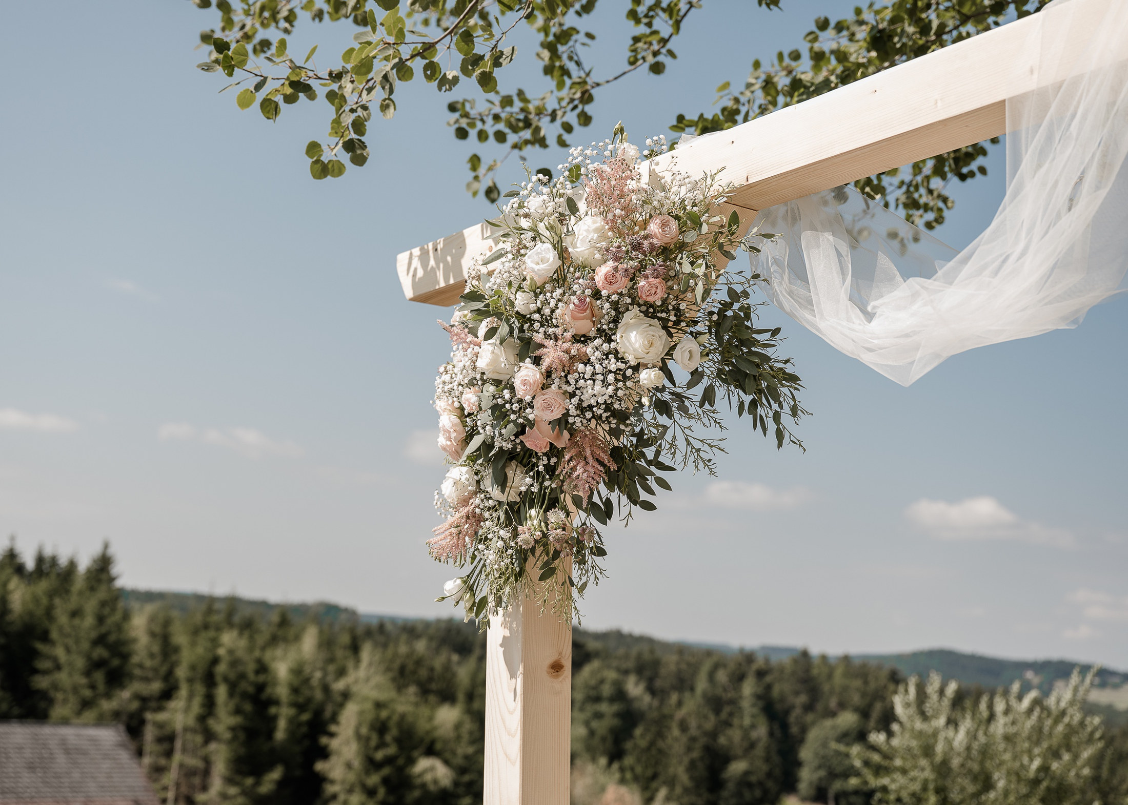 Blumenschmuck mit Rosen und Schleierkraut am Hochzeitsbogen