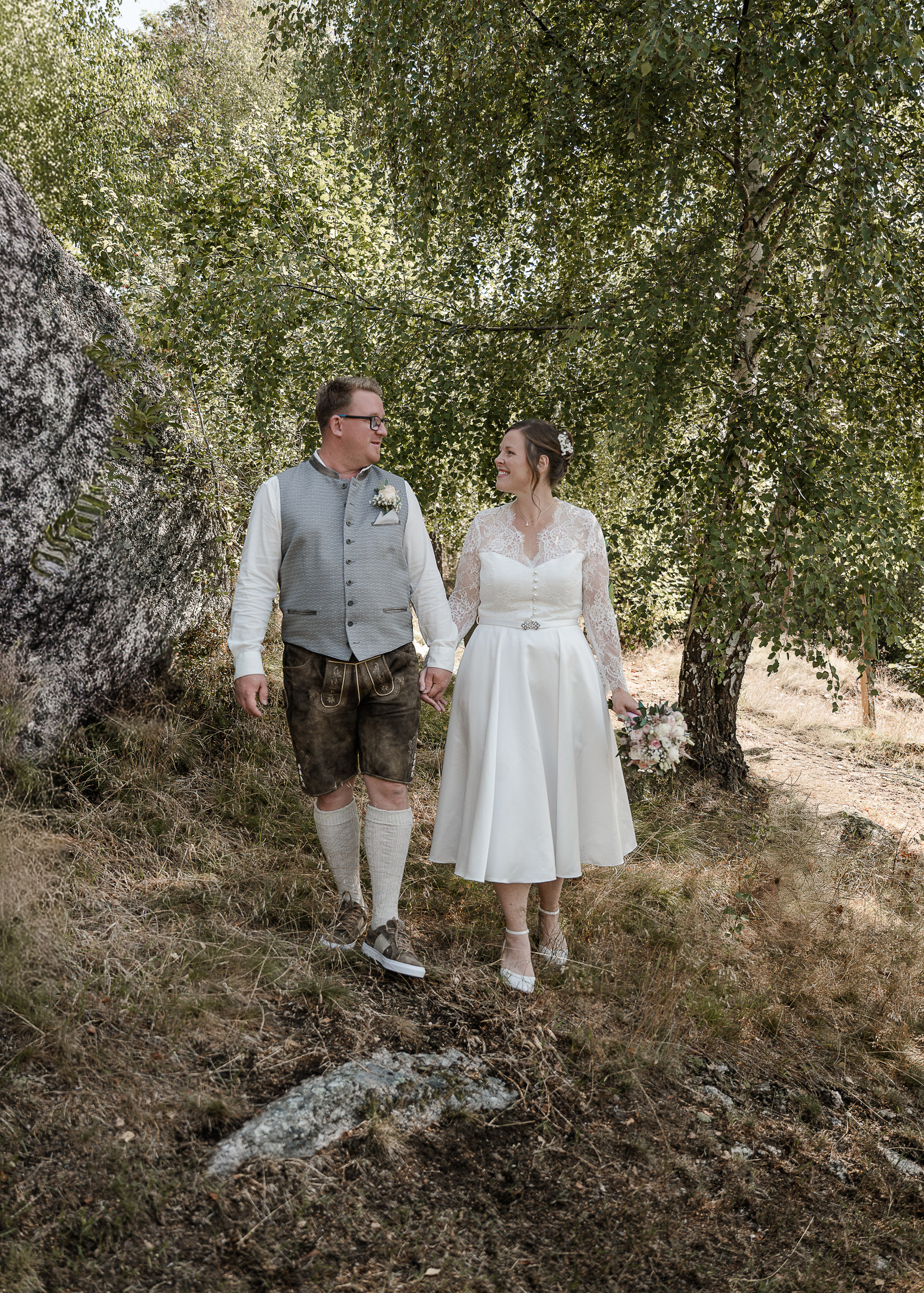 Brautpaar geht Hand in Hand durch den Wald