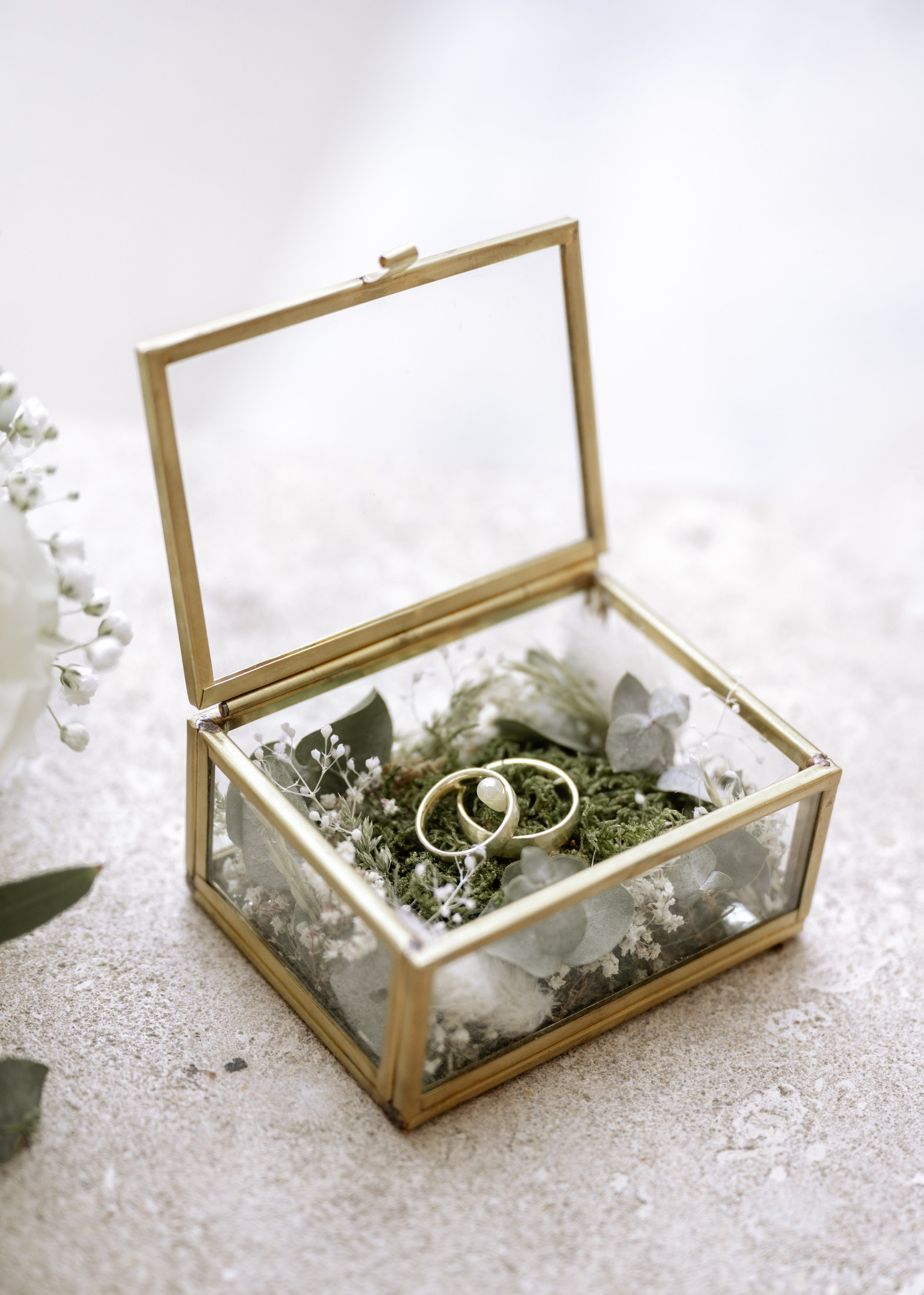 Eheringe in einer Glasschatulle mit Moos und Trockenblumen