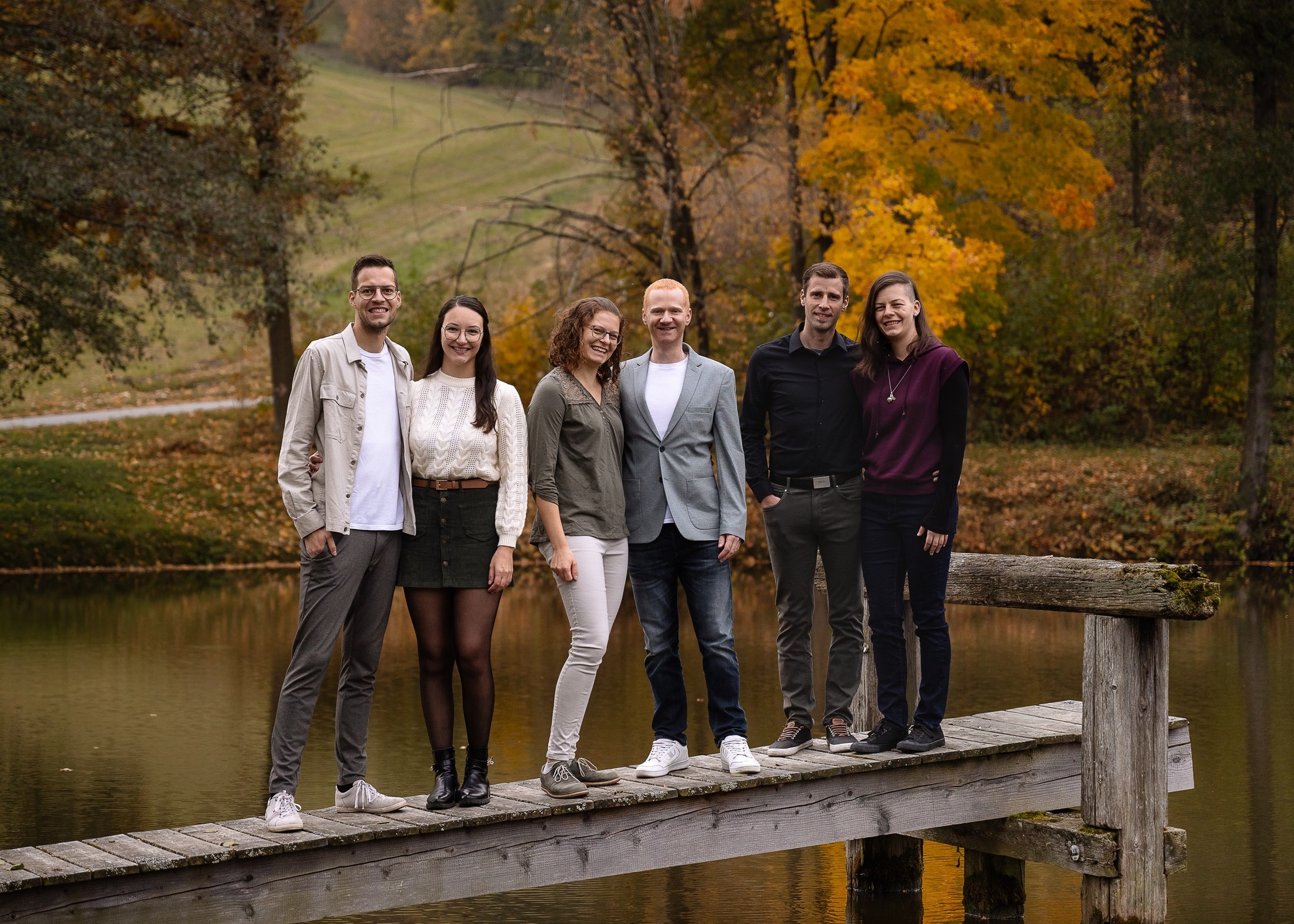 Familie steht auf dem Holzsteg am Teich