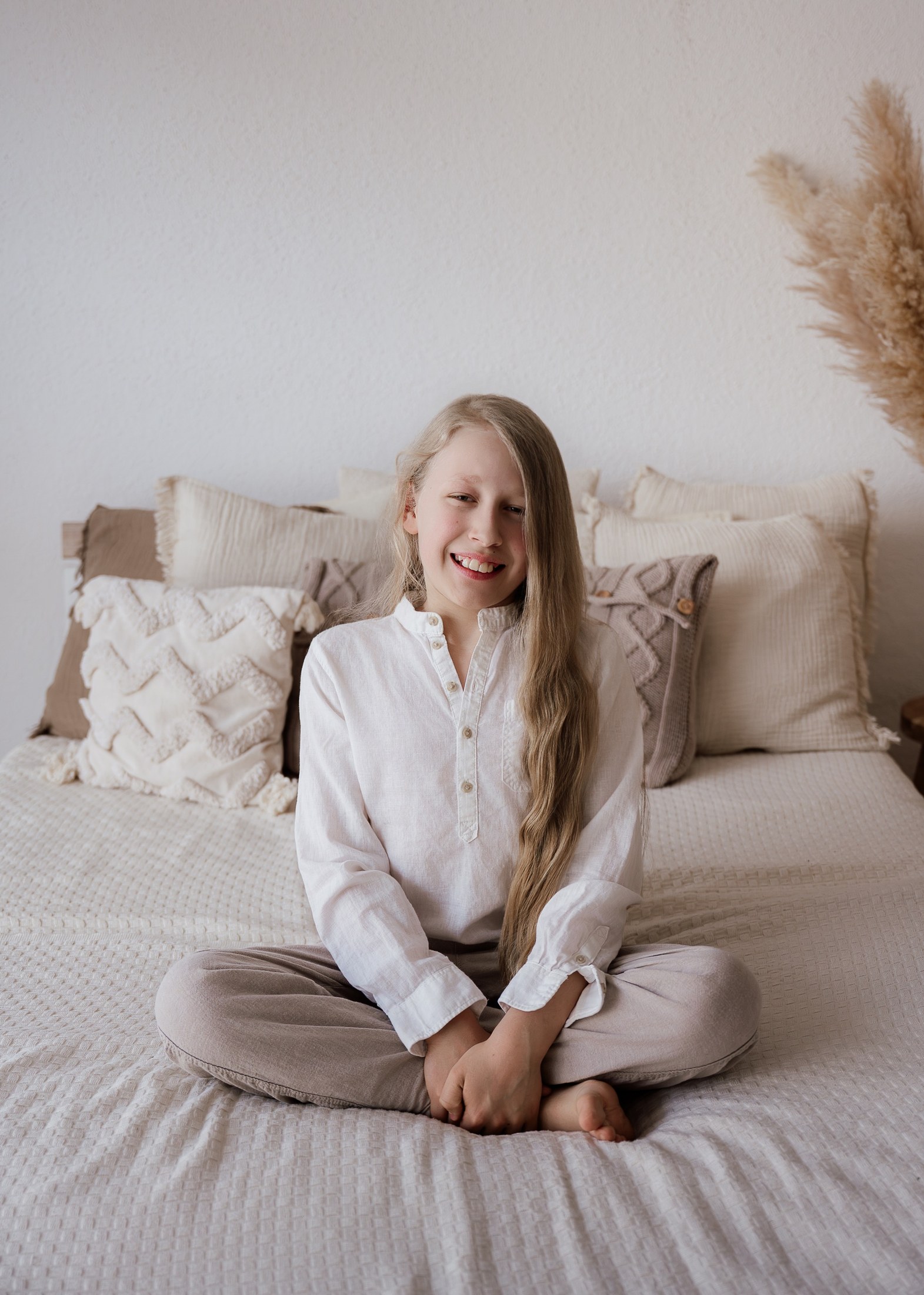 Großer Bruder sitzt lachend auf dem Bett
