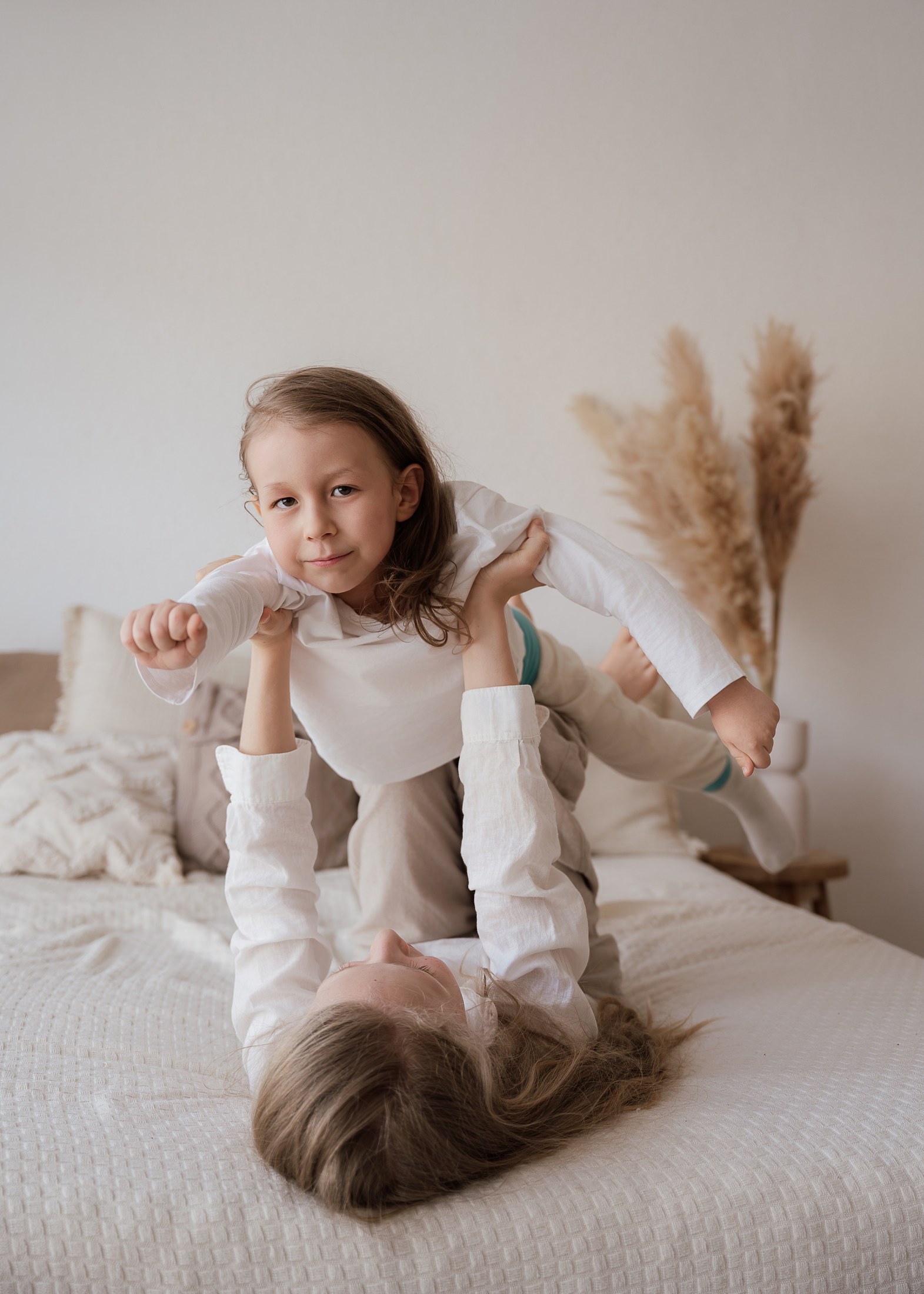 Geschwister spielen Flugzeug auf dem Bett