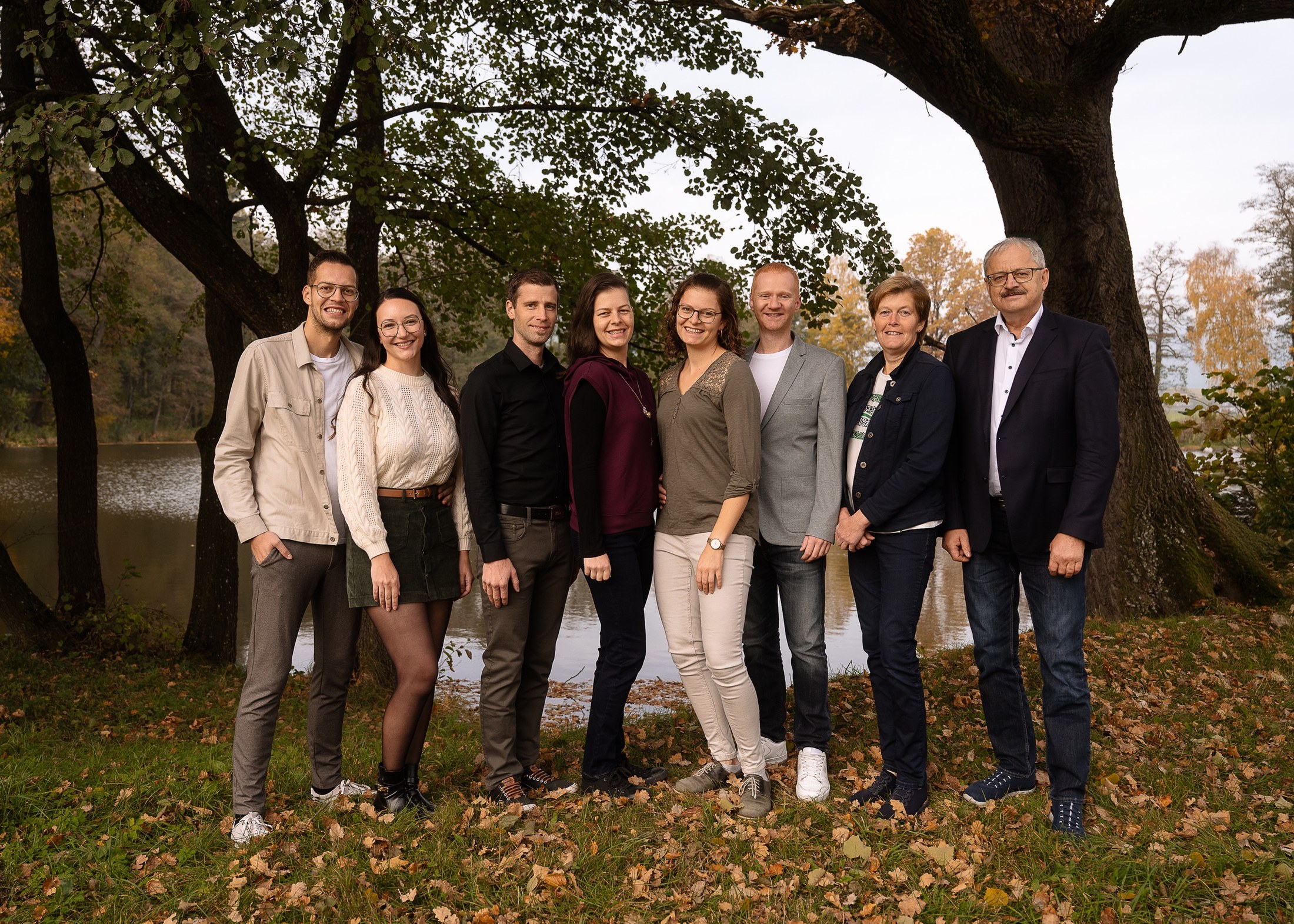 Große Familie steht im Herbst vor dem Teich