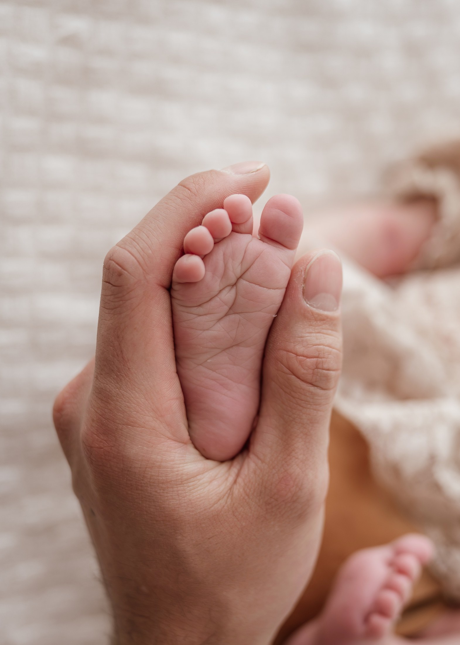 Vater hält den Fuß seines Neugeborenen in der Hand