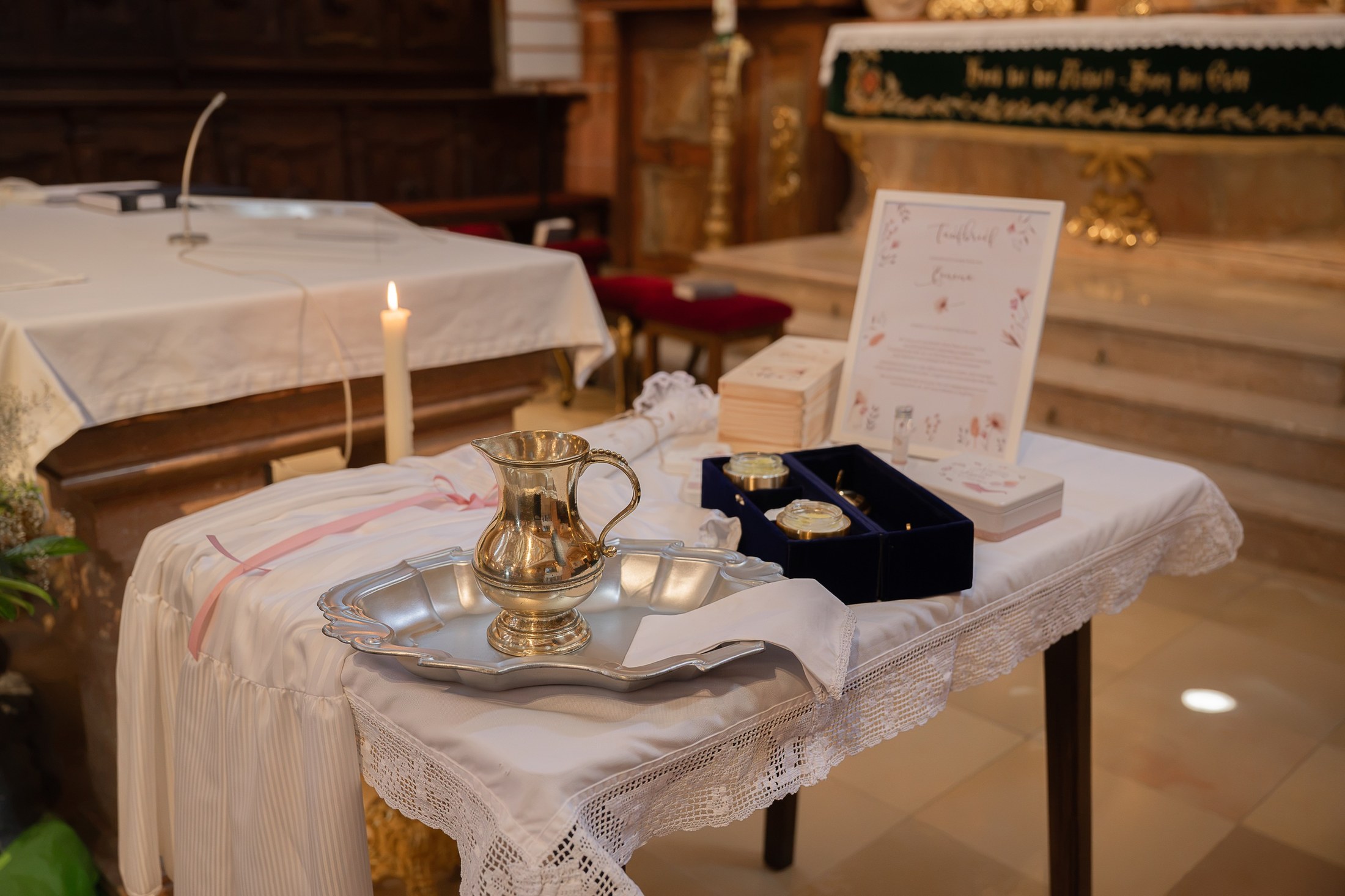 Gabentisch mit Taufkanne, Taufkleid und Taufkerze in der Kirche