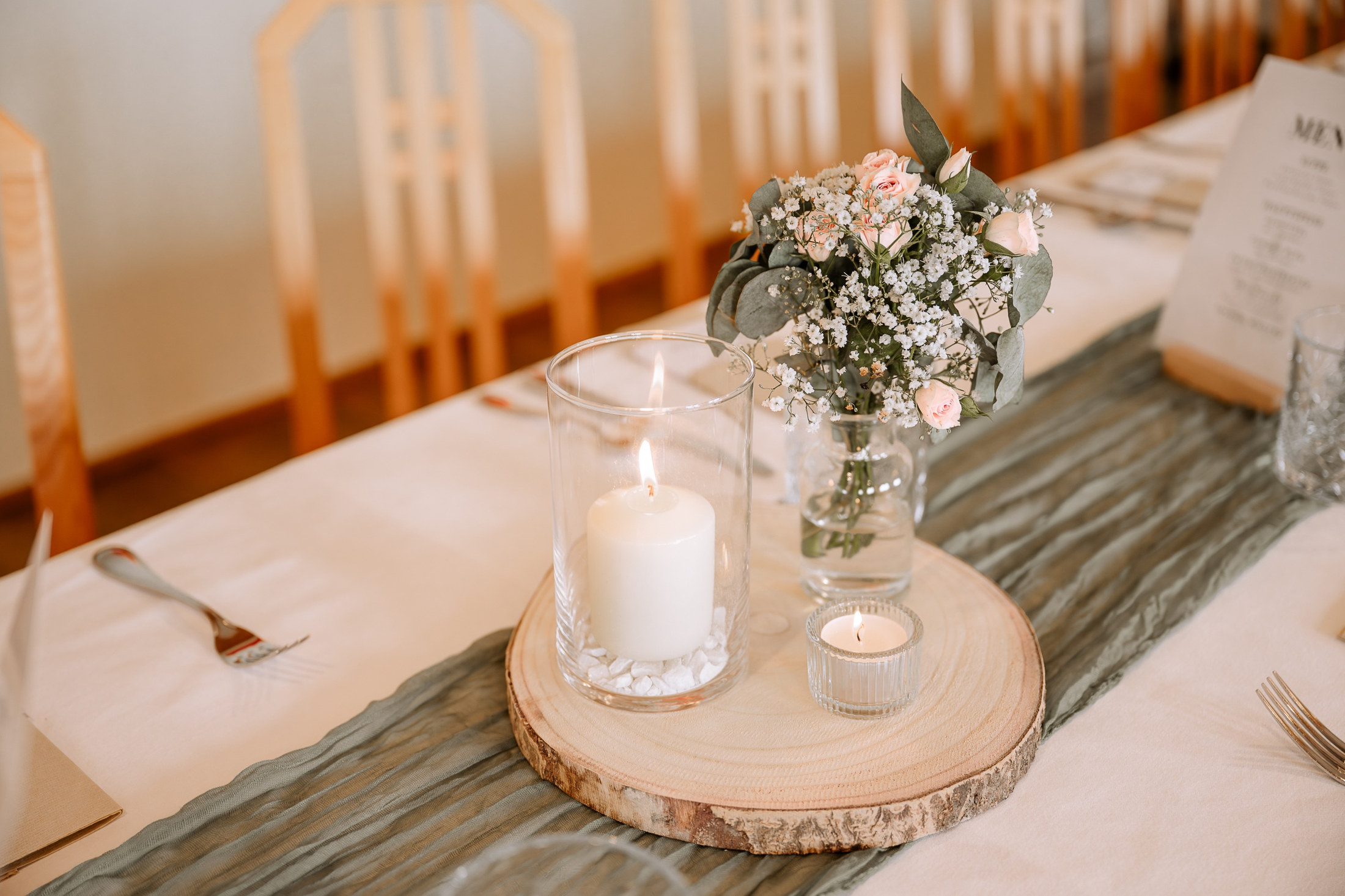 Tischdeko mit Baumscheibe, Kerze und Blumen