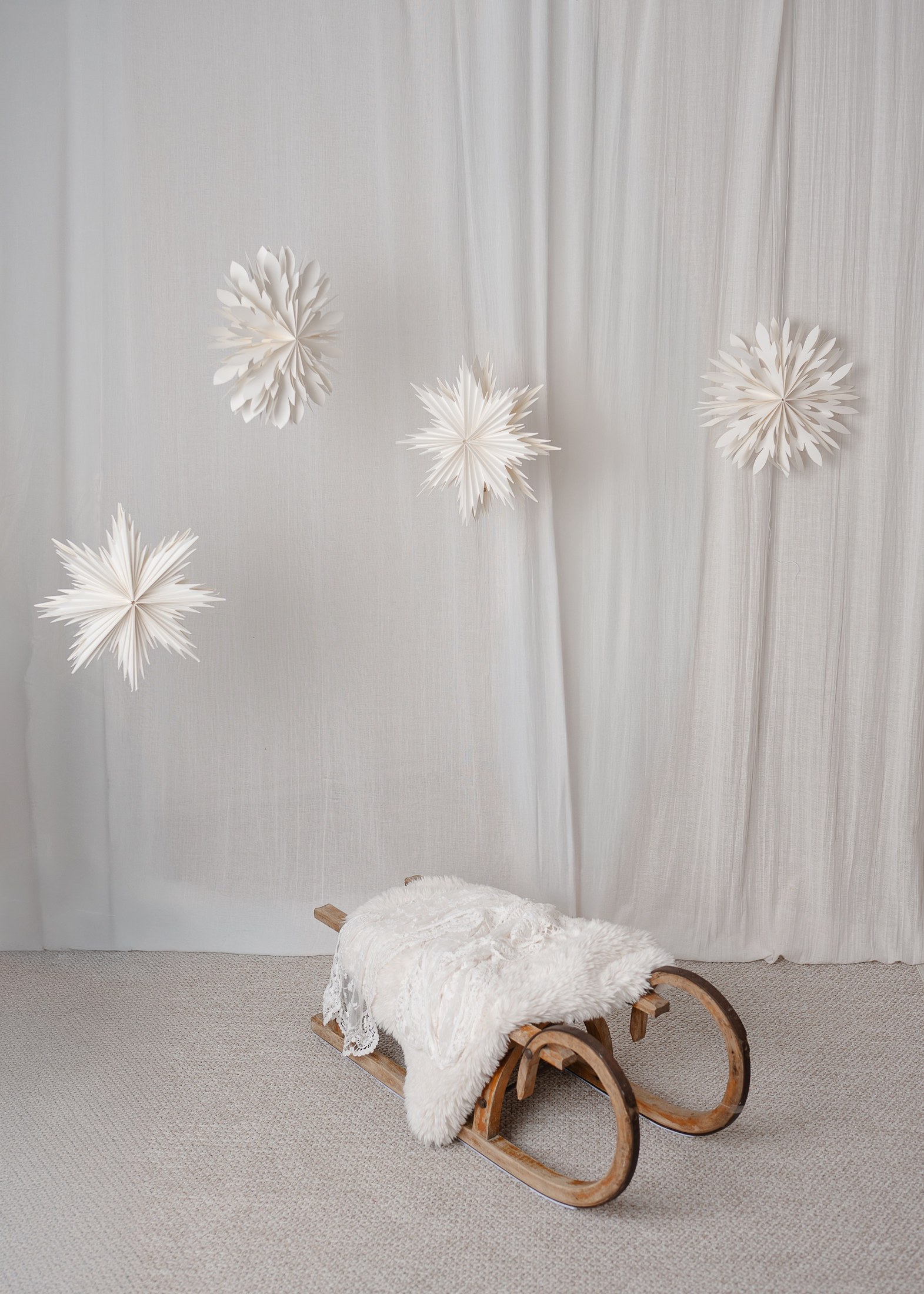 Weihnachtskulisse mit weißen Papiersternen und Holzschlitten