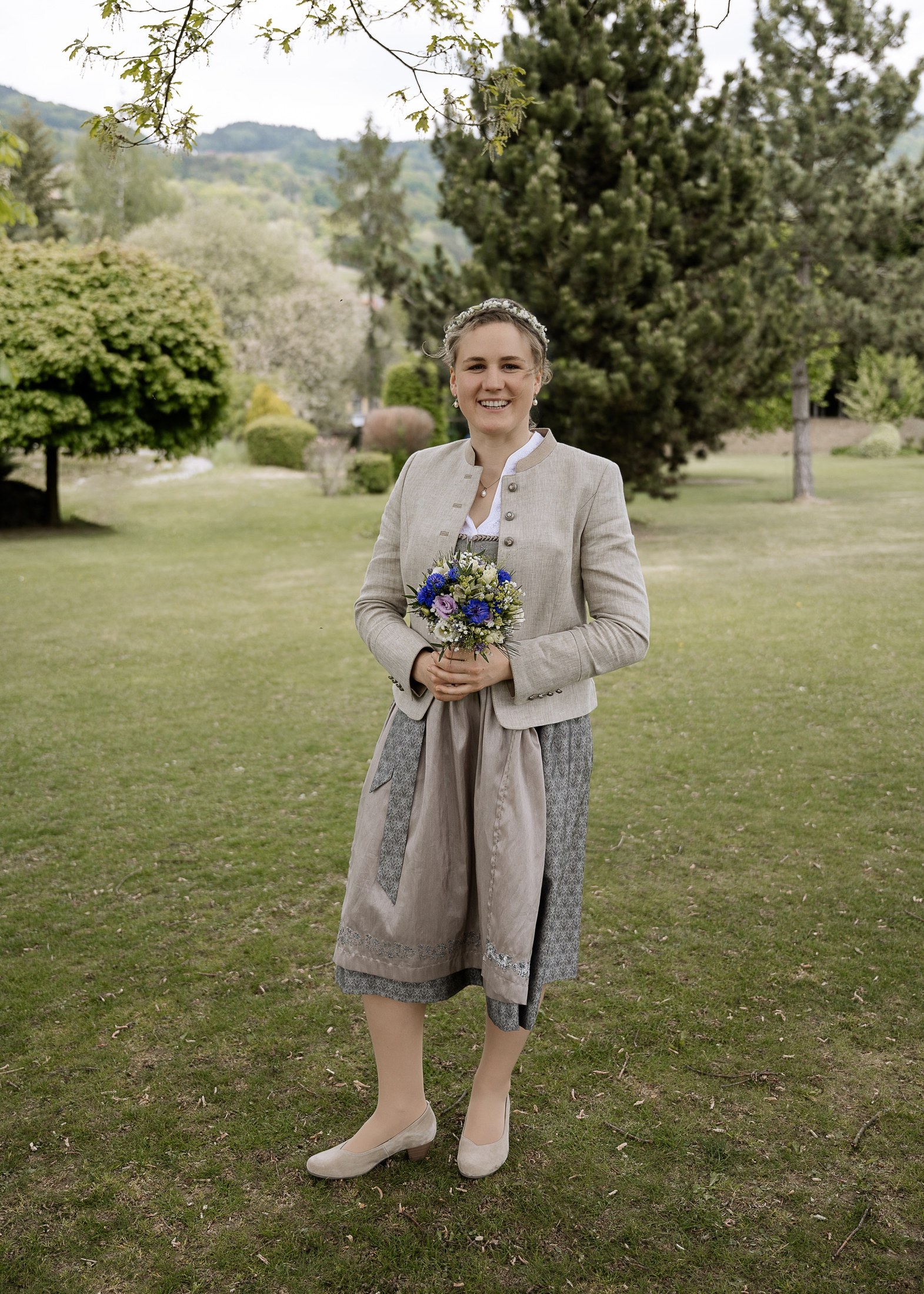 Braut im Dirndl mit Brautstrauß im Park
